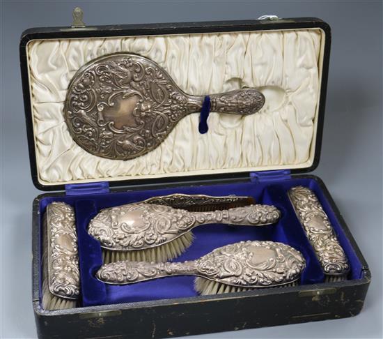 A cased George V repousse silver six piece brush and mirror set, Birmingham, 1927.